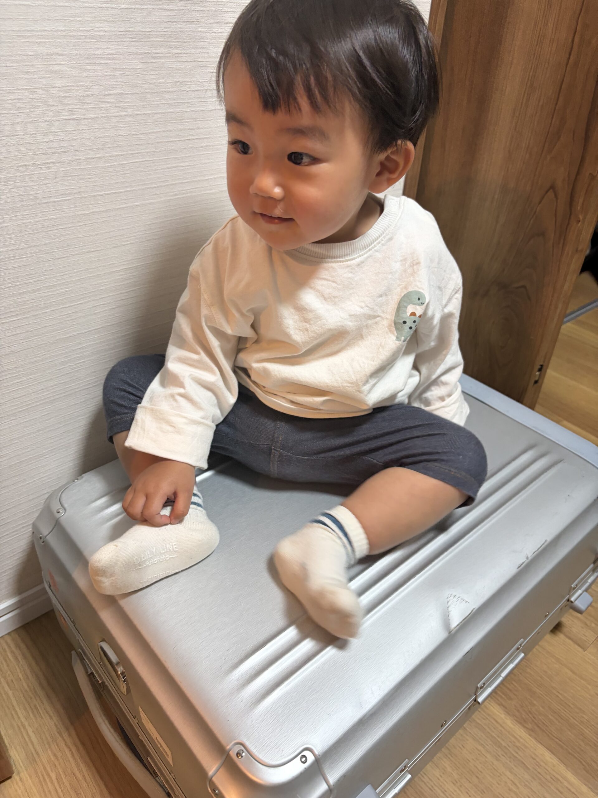 出発前、室内で荷造り中にスーツケースに座る息子